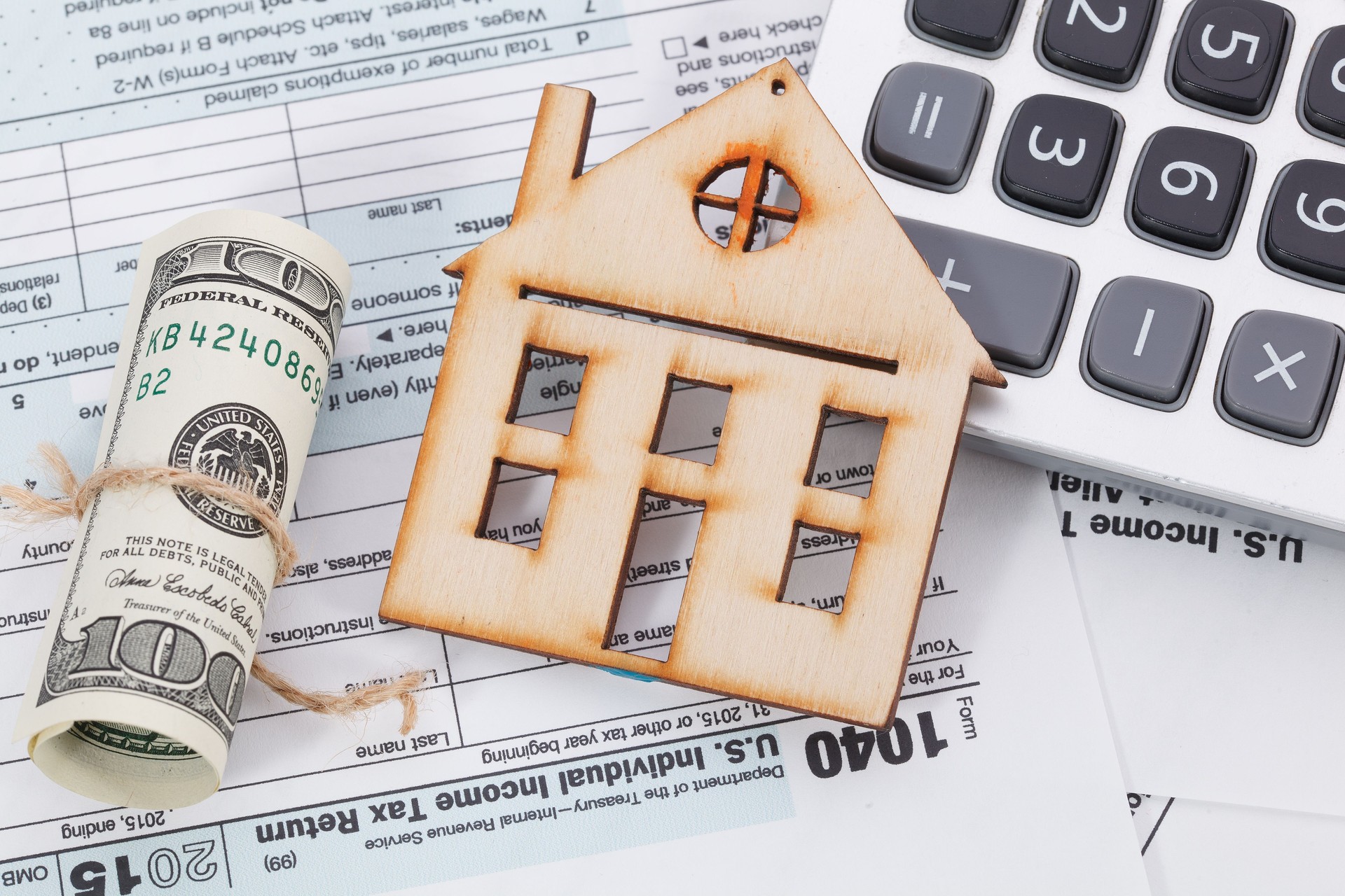 El dinero y calculadora en casa de madera con fondo formulario de impuestos