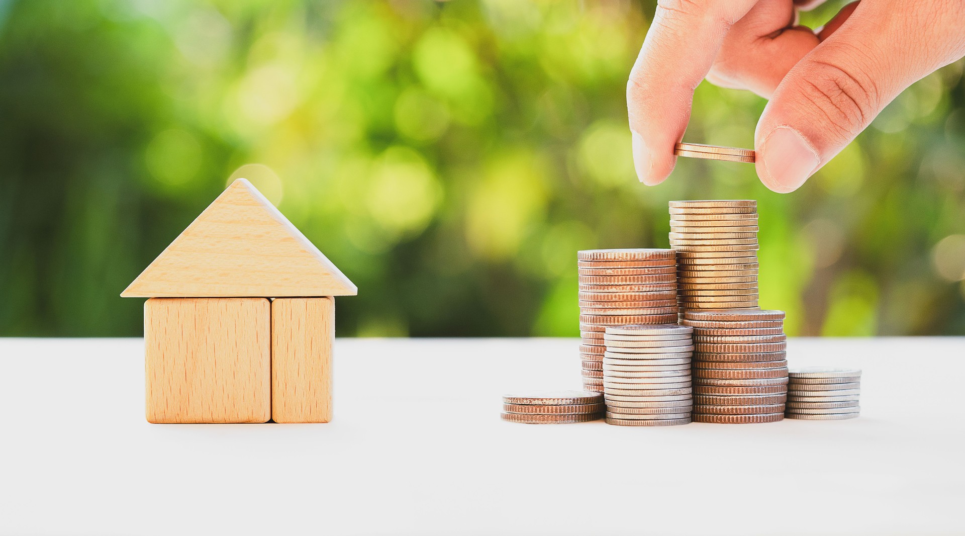 Casa y mano poner monedas de dinero para apilar monedas en la mesa de madera, ahorrar dinero para comprar una casa