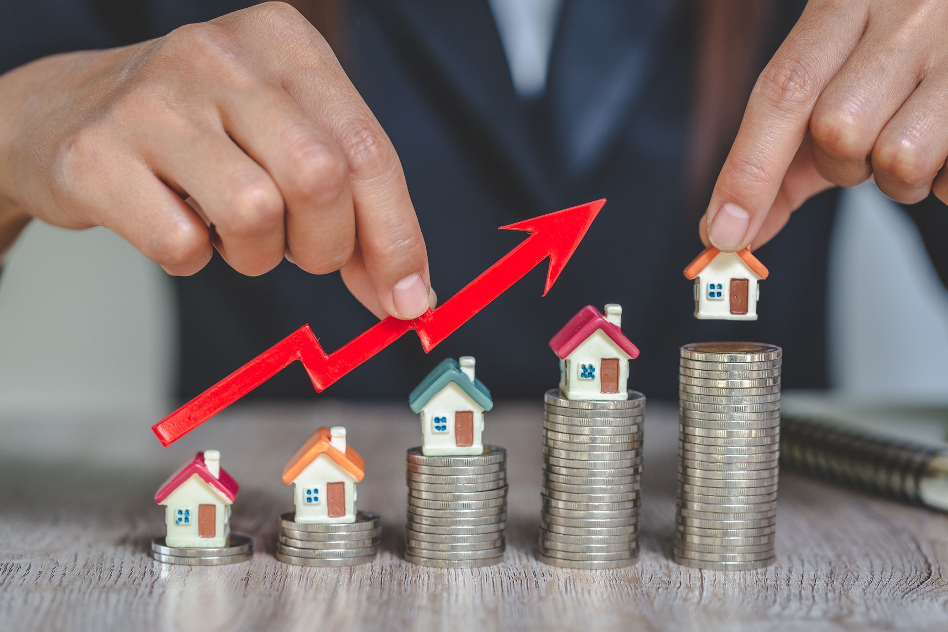 Empresario sosteniendo gráfico sobre la miniatura de la casa creciente, inversión inmobiliaria, financiación hipotecaria de inversión y negocio de préstamos hipotecarios, crecimiento y dinero.