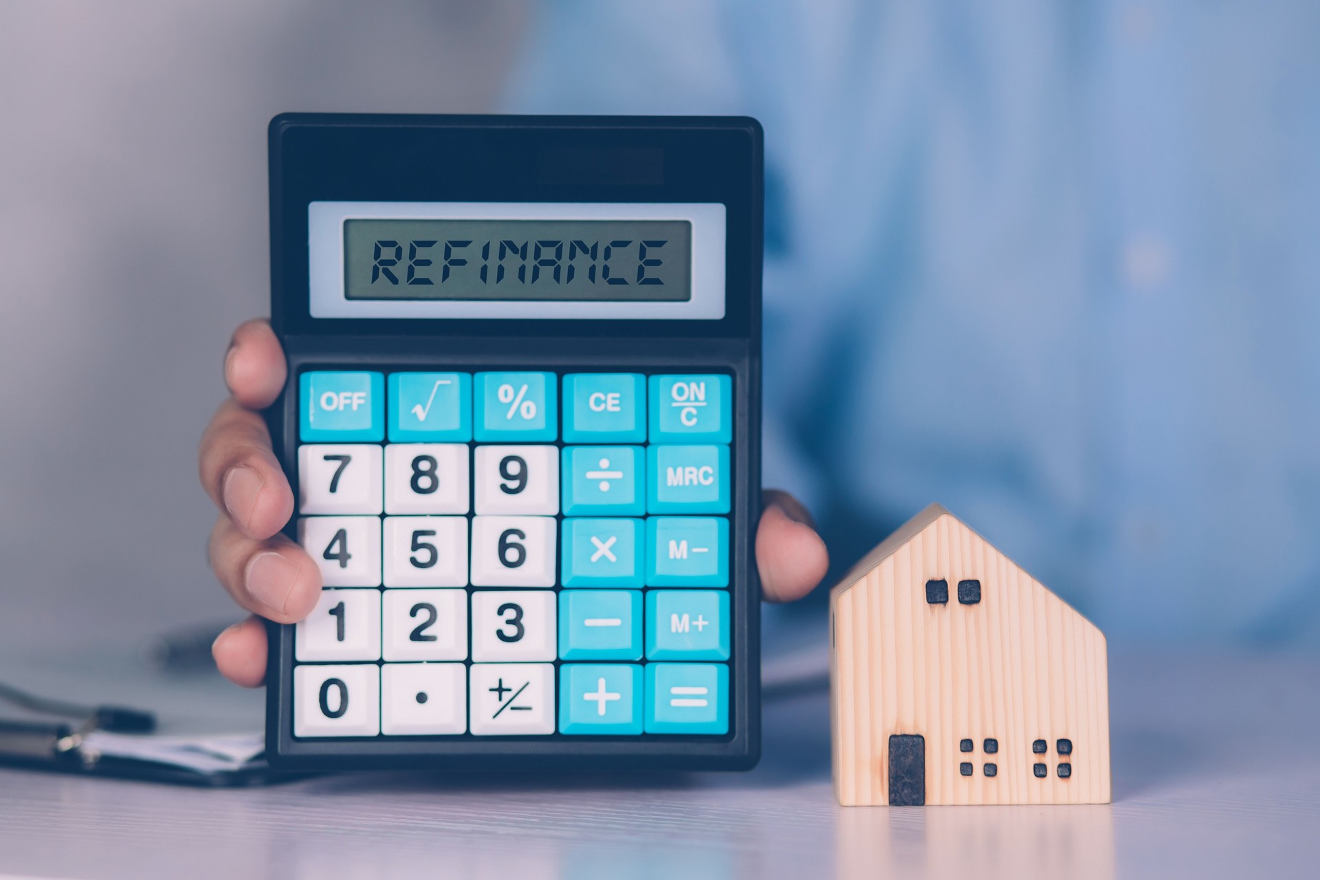 Manos de hombre de negocios que sostiene la calculadora para calcular la casa de refinanciamiento y el gasto para la hipoteca de préstamo, inversión y banca, propiedad y finanzas, bienes raíces y transferencia para la deuda con refinanciamiento.
