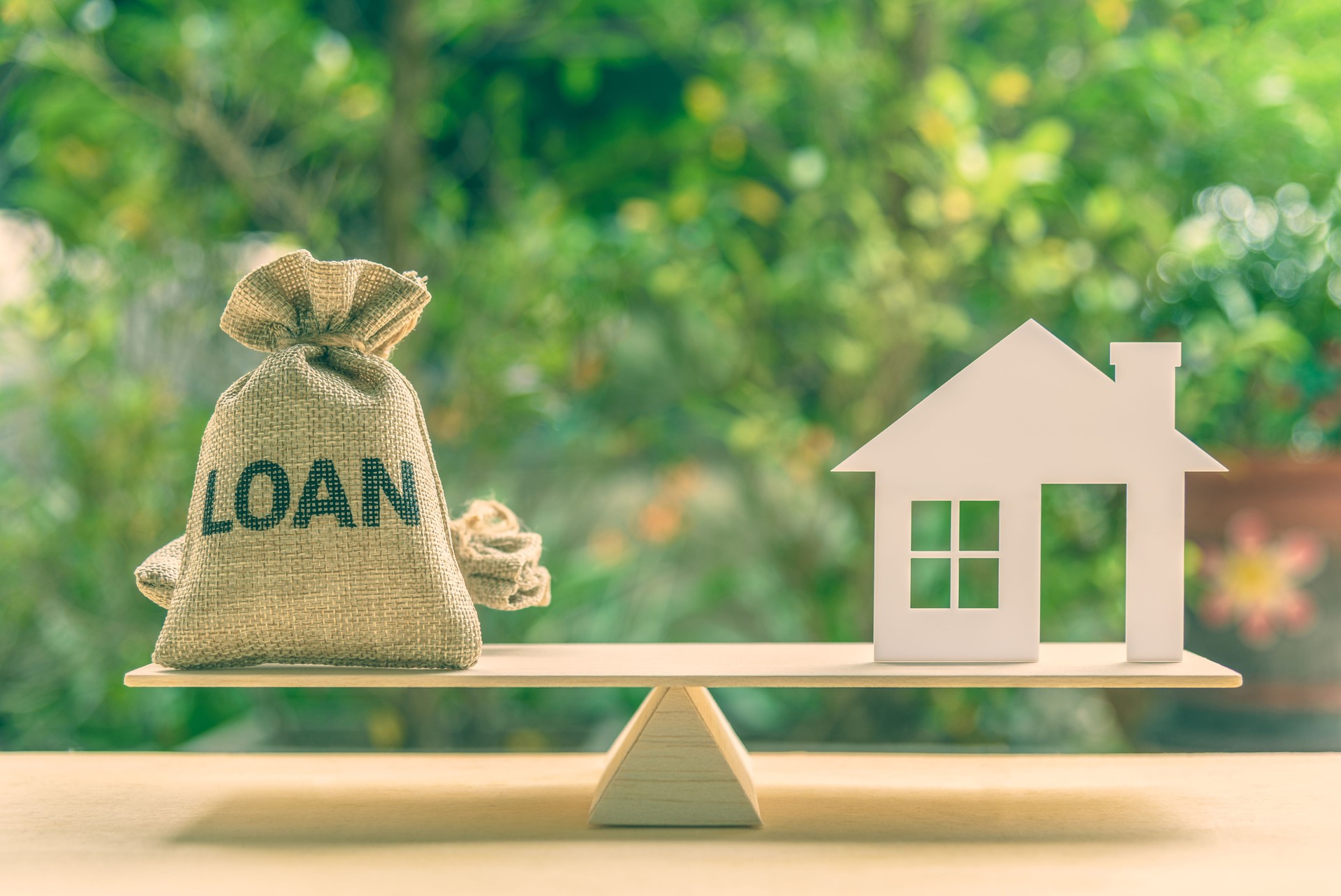 Préstamo hipotecario, hipoteca inversa y ahorro para un concepto inmobiliario: Modelo de casa, bolsa de préstamo en una escala de saldo básica.